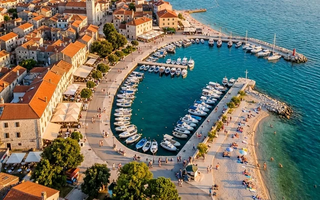 Fažana — ribarsko šetalište, marina puna brodova i zvonik nad šljunkovitom plažom, Istra, Hrvatska
