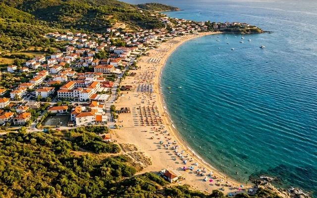 Sarti — duga peščana plaža sa suncobranima uz zeleni greben, letovalište i tirkizno more, istočna Sitonija, Halkidiki